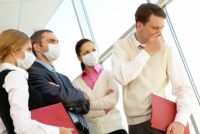 Office workers in surgical masks with coughing coworker.