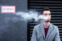 Businessman vaping in front of faciliy