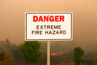 Wildfire hazard sign with wildfire in background