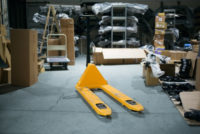 Manual pallet jack in the middle of a cluttered warehouse