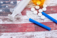 Opioid crisis concept - pills and a needle on a faded American flag